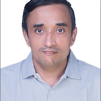 Portrait photo of Qutbuddin Habib, male with short hair, wearing a dark blazer and shirt, looking confident with folded arms